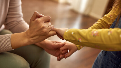 Hands of child and elderly woman making pinkie promise