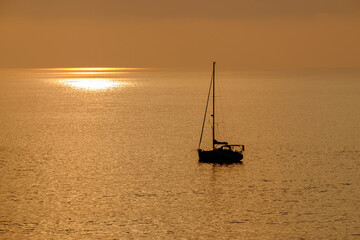 View on the sailboat in the ocean on the sunset in the golden light, close to the beach of Morro Jable on the Canary Island Fuerteventura.