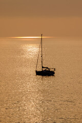 View on the sailboat in the ocean on the sunset in the golden light, close to the beach of Morro Jable on the Canary Island Fuerteventura.