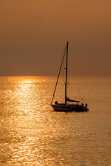 View on the sailboat in the ocean on the sunset in the golden light, close to the beach of Morro Jable on the Canary Island Fuerteventura.