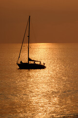 View on the sailboat in the ocean on the sunset in the golden light, close to the beach of Morro Jable on the Canary Island Fuerteventura.