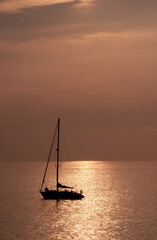 View on the sailboat in the ocean on the sunset in the golden light, close to the beach of Morro...