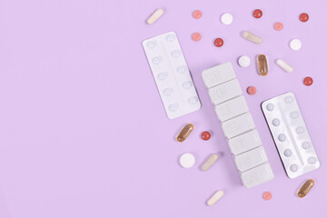 Pills, capsules and pill box on side of violet background with copy space