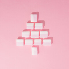 Christmas creative layout with frothy sweet candies that form the shape of a Christmas tree on pastel pink background. Minimal holiday sweet concept with marshmallows.