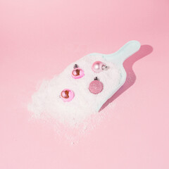 Christmas pastel pink baubles and snow in dustpan on pastel pink background. Winter creative idea....