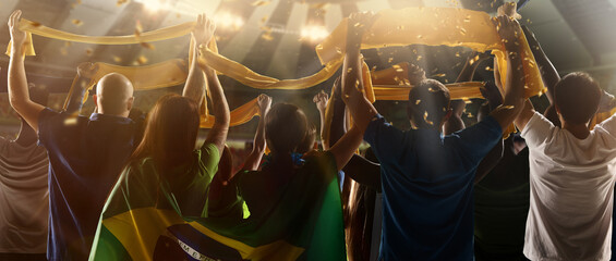 Back view of football, soccer fans from Brazil cheering their team with green yellow state flags...