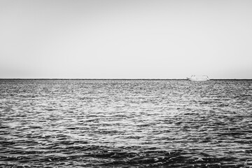 Black-white photography. Alone white boat or ship in silent sea or ocean water