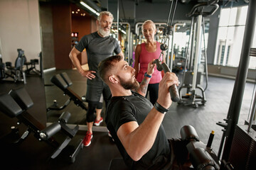 Fototapeta na wymiar Athletic trainer demonstrates how to use power lifting gym equipment