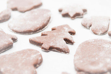 White teflon baking paper full of Christmas shaped gingerbread cookies ready for the oven. Shallow depth of field. SDF.