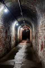 Loft brick tunnel in old German fort, secret passageway with old electricity wiring, Kaliningrad - obrazy, fototapety, plakaty