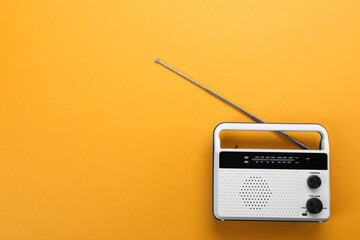 Retro radio receiver on orange background, top view. Space for text
