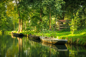 Drei kleine Holzboote  liegen am Ufer eines Kanals im Spreewald