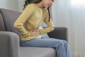 Obraz premium Flatulence asian young woman, girl hand in stomach ache, suffer from food poisoning, abdominal pain and colon problem, gastritis or diarrhoea. Patient belly, abdomen or inflammation, concept.