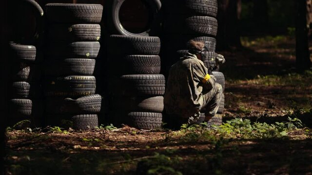 Paintball sport player wearing protective mask aiming gun shelter attack