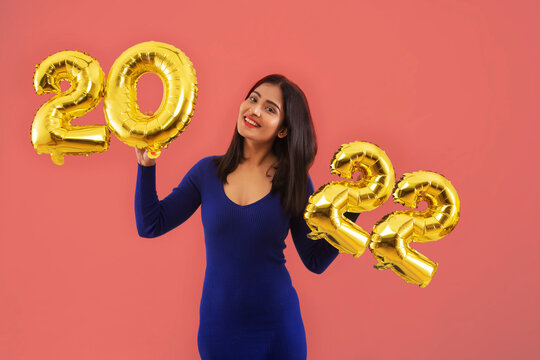 Young woman holding 2022 golden balloons during a new year party. 	