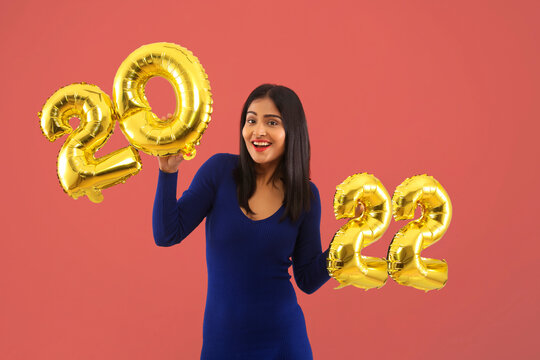 Young woman holding 2022 golden balloons during a new year party. 	