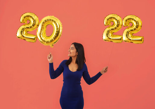 Young woman holding 2022 golden balloons during a new year party. 