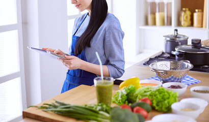 Young woman using a tablet computer to cook in her kitchen