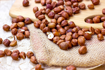 Peeled brown hazelnuts on wooden board and textile background.