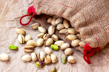 Roasted salted pistachio nuts in nutshell in the textile bag on light background.
