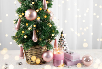 Modern pastel pink color baubles decorations hanging on Christmas tree in home living room, with pink gifts and candle burning. Pastel pink style Christmas concept.
