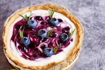 Sฺelective focus of blueberries on Blueberry cheese tart with fresh blueberries and green leaves decorate on the top, delicious homemade cheesecake.