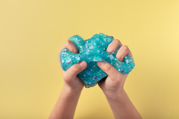 hands squeeze blue slime on yellow background. Antistress toy for kids. closeup. copy space