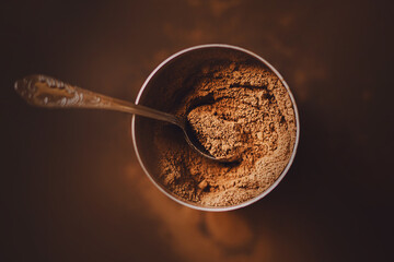 There is a silver teaspoon with patterns in a jar with delicious fragrant crumbly cocoa powder. An...