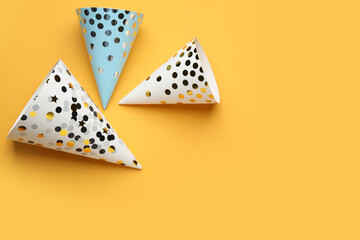 Bright party hats on orange background, flat lay. Space for text