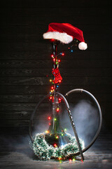 christmas hookah with glowing garland and christmas red hat on dark background