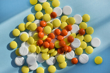 Antiviral white, yellow and orange pills for treatment on a blue background. Flat lay, top view