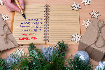 New Year's resolution - Hand holding a pen and writing down plans for the new year: be happy, find...