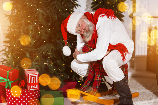 Santa Claus play with toys and left presents gift box under the Christmas tree. New Year's cheerful mood Spirit of Merry Christmas. Senior man with real white beard. Happy holidays concept