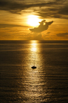Beautiful silhouette of sailboat on sunset at sea with reflection. Summer sun golden hour hot sunset sky.