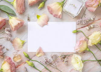Blank paper card between pink flowers and petals top view
