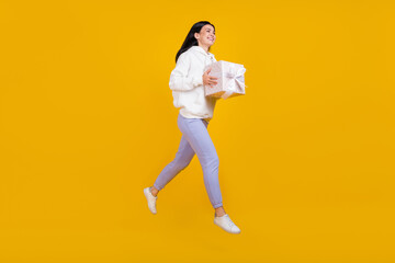 Fototapeta na wymiar Profile photo of positive nice lady jump carry deliver giftbox wear white sweatshirt isolated yellow color background
