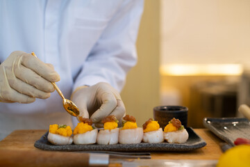 Closeup of chef hands preparing japanese food. Japanese chef making sushi at restaurant. Young chef making traditional japanese sushi omakase on cuting board.