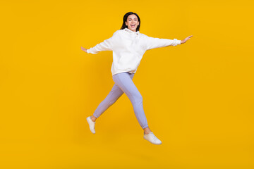 Fototapeta na wymiar Full body photo of cheerful youth lady jump step stroll isolated over bright yellow color background