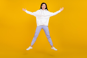 Fototapeta na wymiar Full length photo of excited lady millennial jump hands aside isolated over bright yellow color background