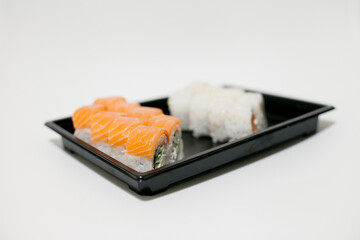 Sushi on a black plate takeout isolated. Japanese food delivery and takeaway.
