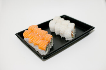 Sushi on a black plate takeout isolated. Japanese food delivery and takeaway.