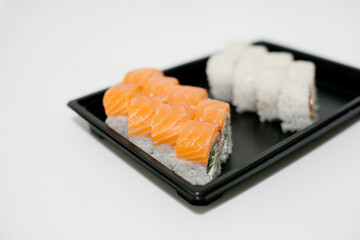 Sushi on a black plate takeout isolated. Japanese food delivery and takeaway.