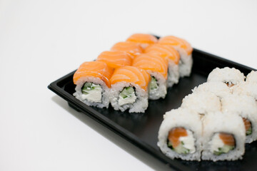 Sushi on a black plate takeout isolated. Japanese food delivery and takeaway.