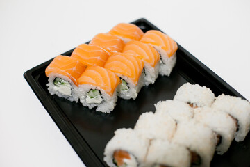Sushi on a black plate takeout isolated. Japanese food delivery and takeaway.