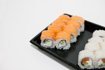 Sushi on a black plate takeout isolated. Japanese food delivery and takeaway.