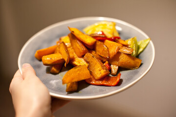 Baked sweet potatoes and vegetables on a plate for dinner.  Homemade healthy vegan food.