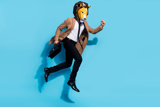 Full length photo of bizarre incognito guy lion mask jump up hold hand bag hurry partners briefing isolated over blue color background