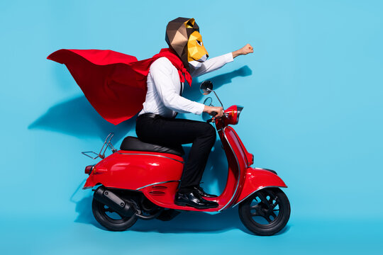 Full body profile side photo of weird lion mask wear red mantle guy ride scooter protect planet isolated over blue color background