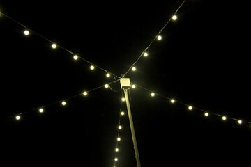 light bulbs on string wire hanging on pole against the background of darkness