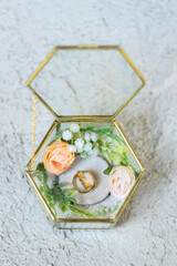 Wedding rings of the bride and groom with decorative glass box and flower. The wedding ring is decorated with flowers and a glass box for wedding rings. Wedding preparation holy matrimony